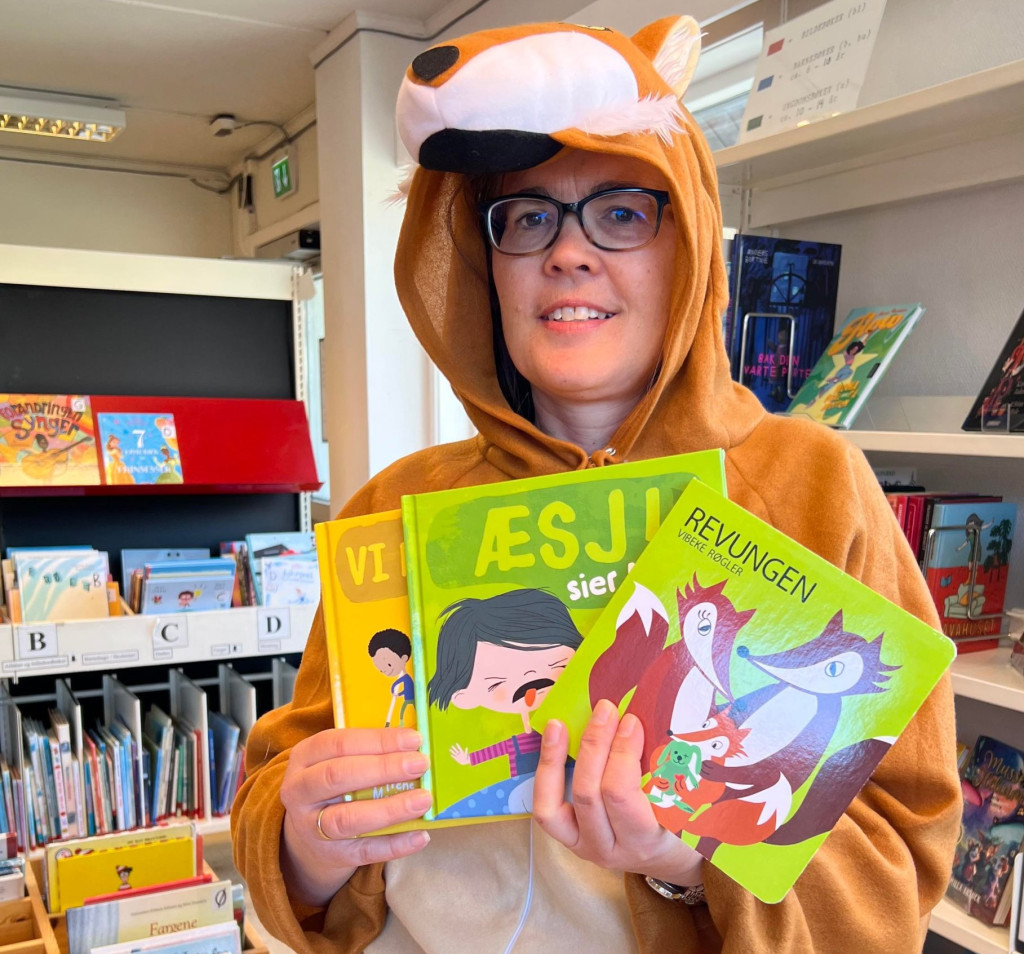 Biblioteksjefen Astrid Sandersen i revekostyme viser fram tre barnebøker