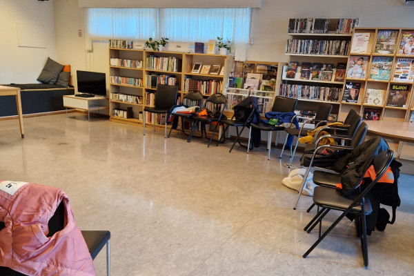 Stoler satt i ring i biblioteket. På stolene har skolebarna som er på besøk hengt fra seg jakker