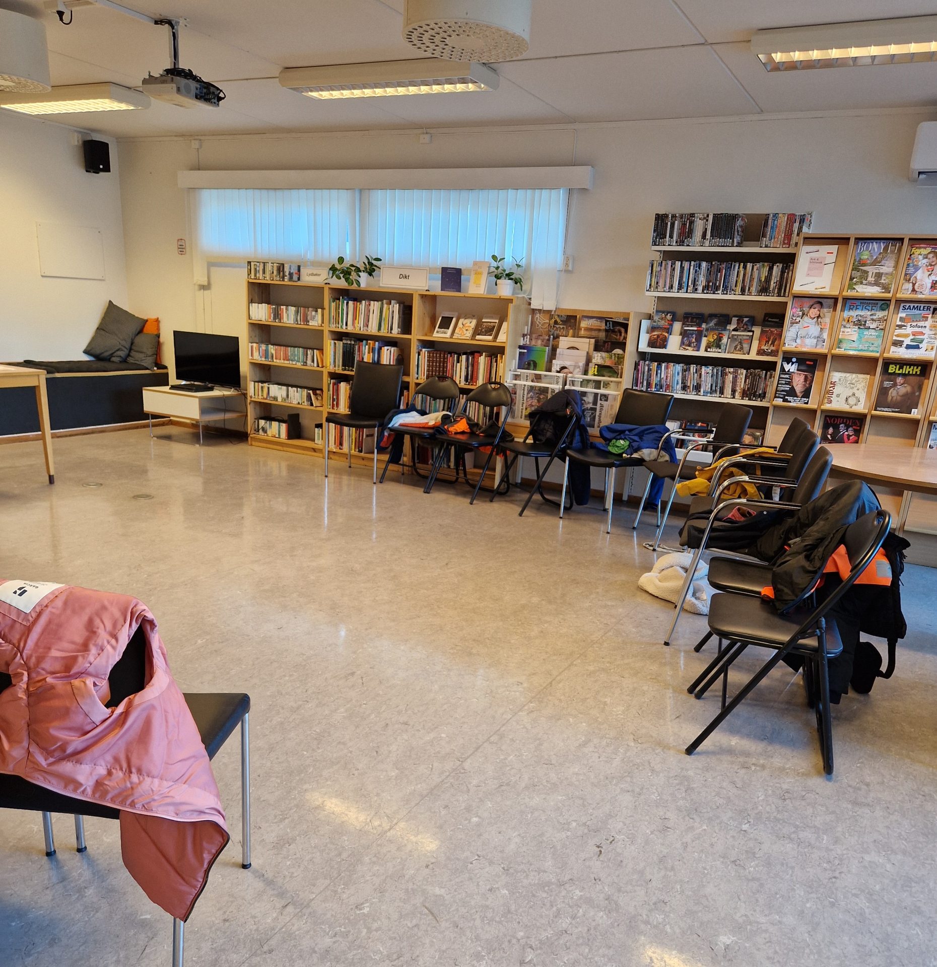 Stoler satt i ring i biblioteket. På stolene har skolebarna som er på besøk hengt fra seg jakker