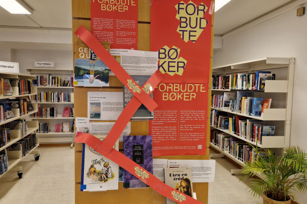 Bilde av utstilling av bøker og plakat på rød bakgrunn med teksten "forbudet-bøker" Bøker med rødt banner over.