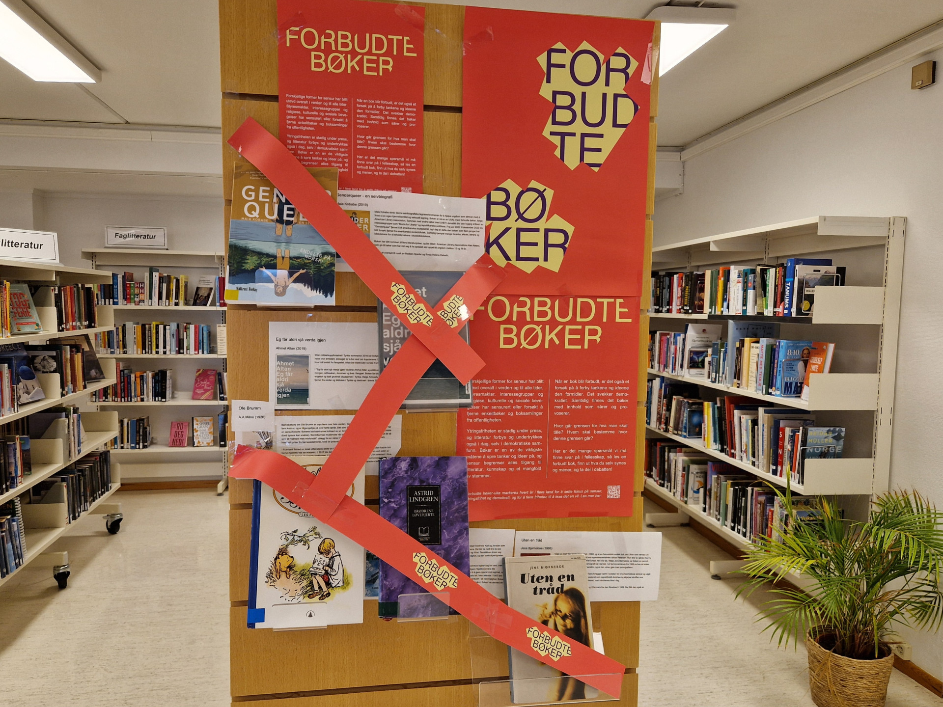 Bilde av utstilling av bøker og plakat på rød bakgrunn med teksten "forbudet-bøker" Bøker med rødt banner over.