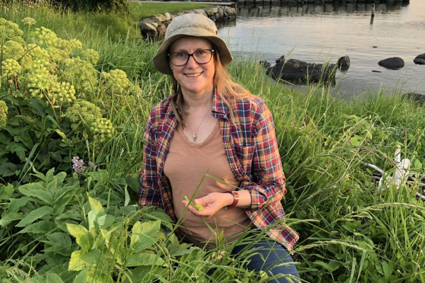 Bilde av dame med hatt med strandkvannplanter i sjøkanten